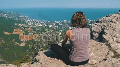 坐在莲花位置的女人练习<strong>瑜伽动作</strong>或冥想，并在山上举起她的手臂。